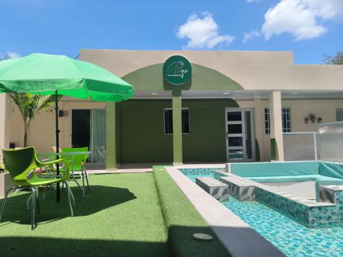 a house with a swimming pool and a green umbrella at Villa campestre Meqo in Ríohacha