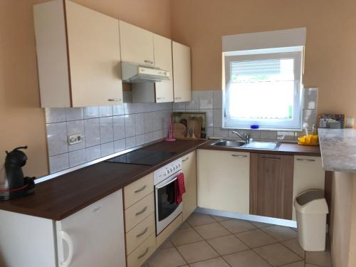 kuchnia z białymi szafkami, zlewem i oknem w obiekcie Apartments Villa Engeli w mieście Vir