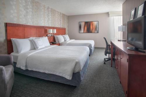 a hotel room with two beds and a flat screen tv at Courtyard Wilmington Downtown in Wilmington