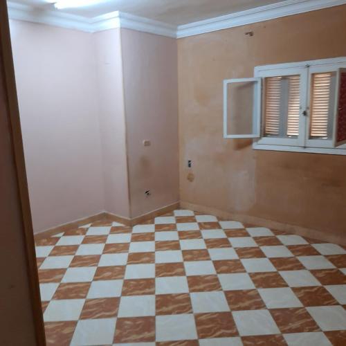 an empty room with a checkered floor and a window at شقه للايجار جاهزه بالكامل in Cairo