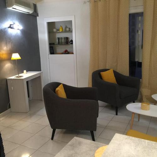 ein Wohnzimmer mit 2 Stühlen und einem Tisch in der Unterkunft Appartement chaleureux proche de la croisette in Cannes