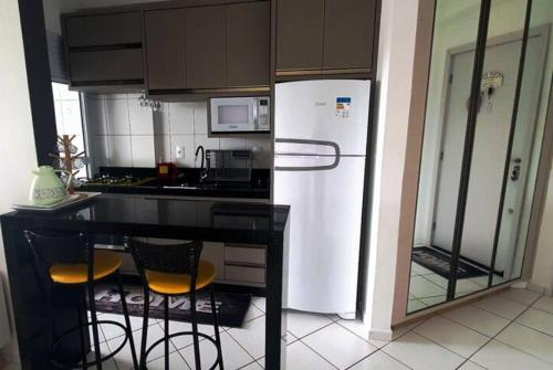 a kitchen with a white refrigerator and a counter with chairs at Apartamento próximo a praia. in Laguna