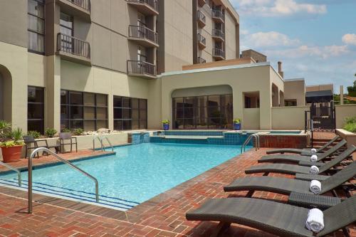 - une piscine avec des chaises longues devant un bâtiment dans l'établissement Charlotte Marriott SouthPark, à Charlotte