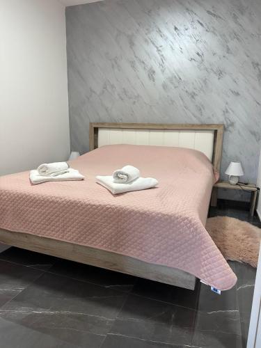 a bedroom with a pink bed with two towels on it at Romantika 1 in Ostrovo