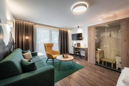 ein Wohnzimmer mit einem grünen Sofa und einem Tisch in der Unterkunft Vitaurina Royal Hotel in Mühlen in Taufers