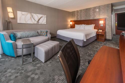 pokój hotelowy z łóżkiem i kanapą w obiekcie Courtyard by Marriott Fairfax Fair Oaks w mieście Fairfax
