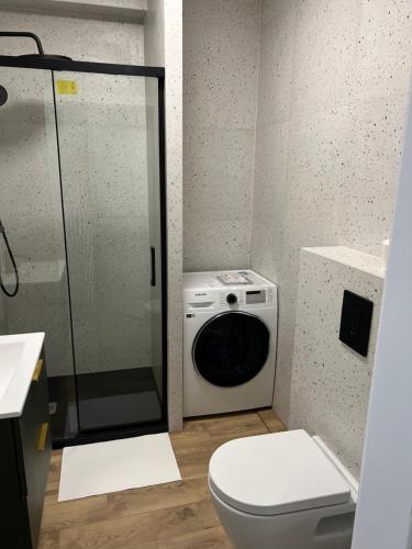 ein Badezimmer mit einer Waschmaschine und einem WC in der Unterkunft Aquarius Kilińskiego 1 in Grodzisk Mazowiecki