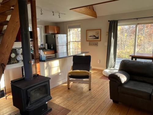 a living room with a fireplace and a stove at Not-so-tiny, Tranquil, Pond front Bungalow in Canaan