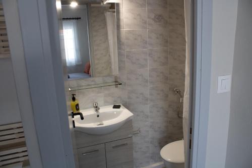 a bathroom with a sink and a toilet and a mirror at POSIDONIA RESORT No7 in Nea Vrasna