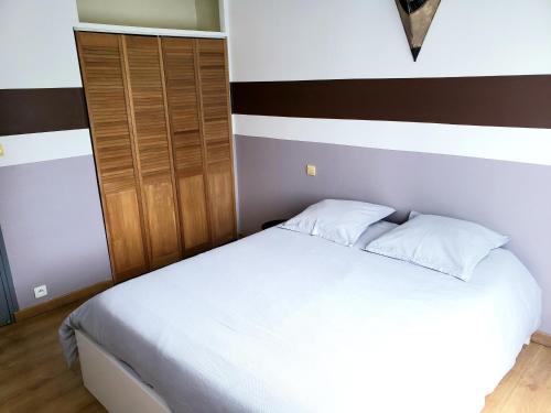 um quarto com uma cama branca e um armário de madeira em Orteils au soleil jardin parking em Nîmes