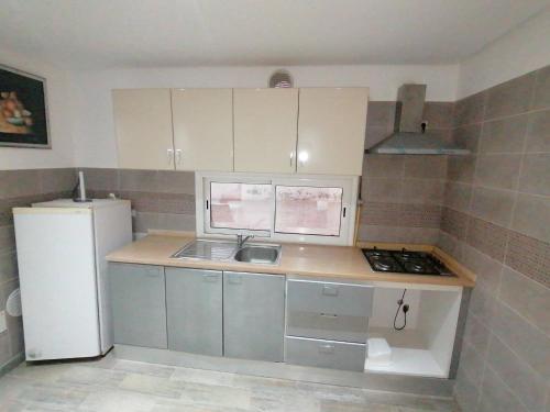 a small kitchen with a sink and a refrigerator at Résidence le corail de chat meriem in Sousse