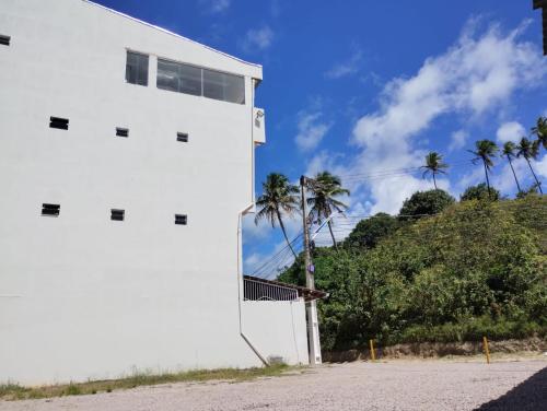 a white building with palm trees in the background at Pousada La Belle in Maragogi