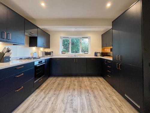 cocina con armarios negros y suelo de madera en Surrey Hills Lodge, en Ewhurst