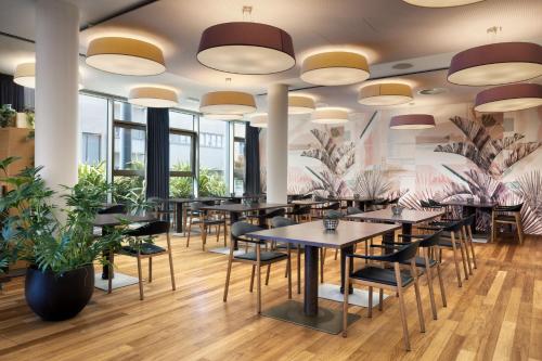 a restaurant with tables and chairs and large windows at Four Points Sheraton Bolzano Bozen in Bolzano