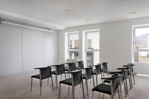 a room with a row of black chairs and tables at Four Points Sheraton Bolzano Bozen in Bolzano