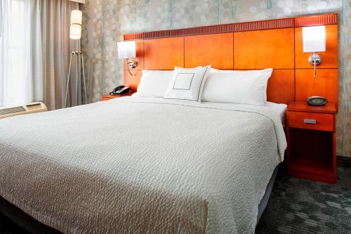 a hotel room with a large bed with white pillows at Courtyard Hamilton in Hamilton