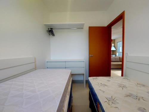 um pequeno quarto com uma cama e um espelho em Apartamento com piscina aquecida e churrasqueira em Ubatuba