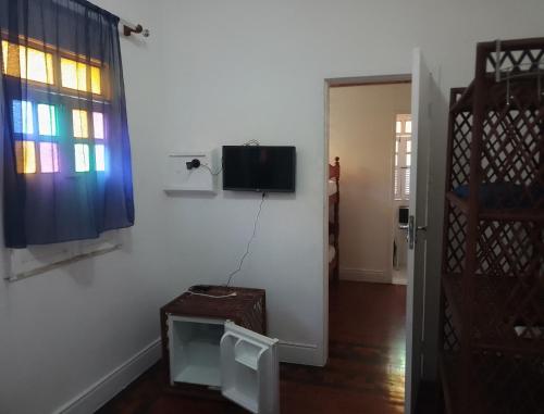 Habitación con TV en la pared y ventana. en Pousada Bamboo da Barra en Salvador