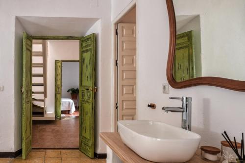 ein Badezimmer mit einem weißen Waschbecken und einem Spiegel in der Unterkunft Encanto Guesthouse in Canillas de Aceituno
