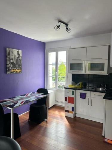 L’Escale: Appartement complet في تور: مطبخ مع طاولة وجدار أرجواني