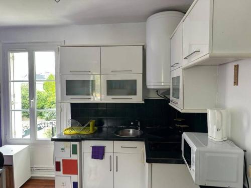 L’Escale: Appartement complet في تور: مطبخ بدولاب أبيض وقمة كونتر أسود