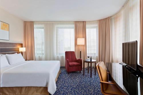 ウィーンにあるコートヤード バイ マリオット ヴィエナ プラーター/メッセの白いベッドと赤い椅子が備わるホテルルームです。