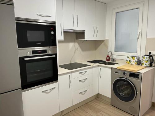 a kitchen with white cabinets and a washer and dryer at Apartamento Gallaecia Lux in Santiago de Compostela