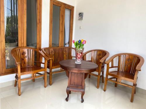 einen Tisch mit vier Stühlen und eine Vase mit Blumen darauf in der Unterkunft Rumah Yosua in Palbapang