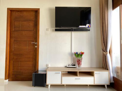 sala de estar con TV en la pared y puerta en Rumah Yosua, en Palbapang