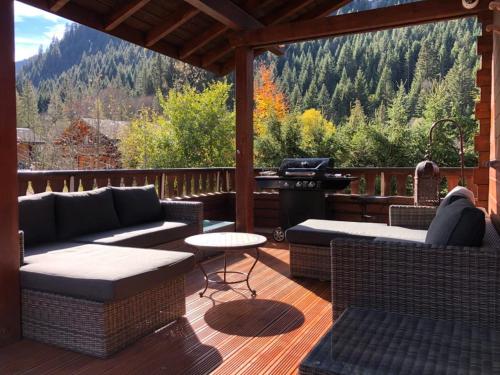a patio with couches and a grill on a deck at Les Sapins - Welcoming chalet for 14p with hot tub in Châtel