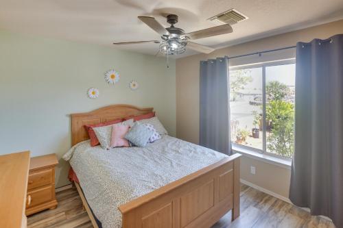 a bedroom with a bed with a ceiling fan and a window at Lovely Bullhead City Retreat with Patio and Grill! in Bullhead City