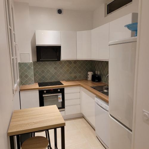 Elle comprend une petite cuisine avec des placards blancs et une table en bois. dans l'établissement BLUMENTHAL, à Épinay-sur-Seine