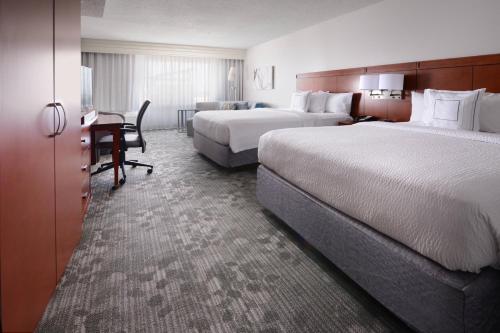 a hotel room with two beds and a desk at Courtyard Marriott Houston Pearland in Pearland
