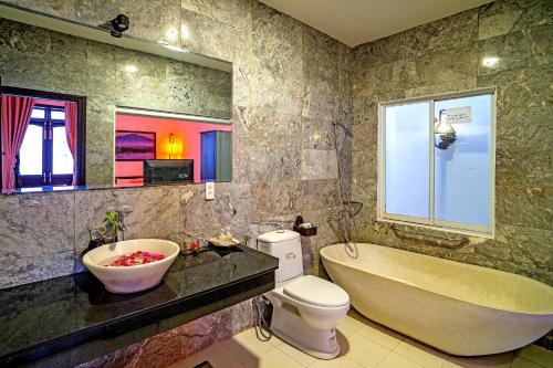 a bathroom with a tub and a toilet and a sink at The House 36 in Hoi An