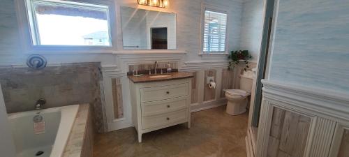 a bathroom with a sink and a tub and a toilet at Pierhouse Bed & Breakfast in Kill Devil Hills