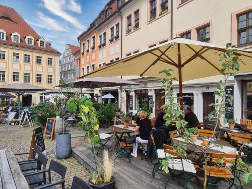 a group of people sitting at tables under an umbrella at Altstadt Domizil in Pirna