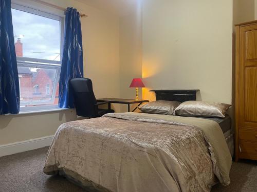 a bedroom with a bed and a chair and a window at Transformative housing Laurie avenue in Nottingham