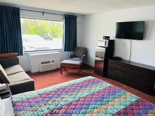 a hotel room with a bed and a tv at Lively Inn and Suites - Sudbury in Naughton
