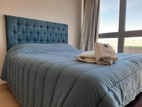 een blauw bed met een knuffeldier erop bij M O R A Home & Office in Cipolletti