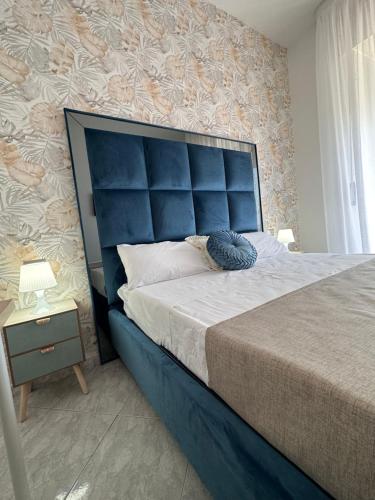 a bedroom with a large bed with a blue headboard at Airport Seaview Rooms in Naples