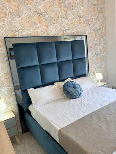 a large bed with a blue headboard in a bedroom at Airport Seaview Rooms in Naples