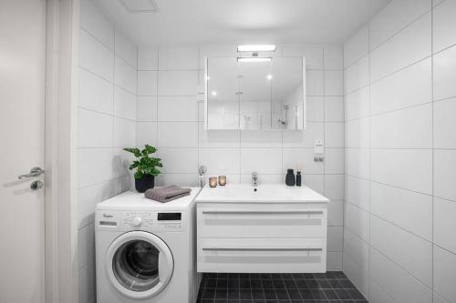 a white bathroom with a washing machine and a sink at Demims Apartments Lorenskog centre -- Ahus & SNØ & Parking in Lorenskog