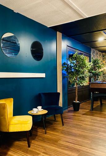 a room with a blue wall with a chair and a table at Kyriad Direct Laon in Laon