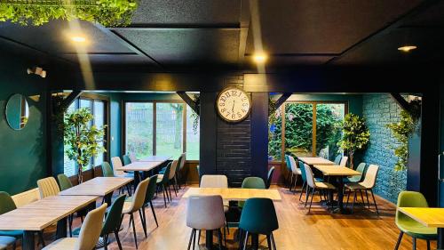 un restaurante con mesas y sillas y un reloj en la pared en Kyriad Direct Laon en Laon