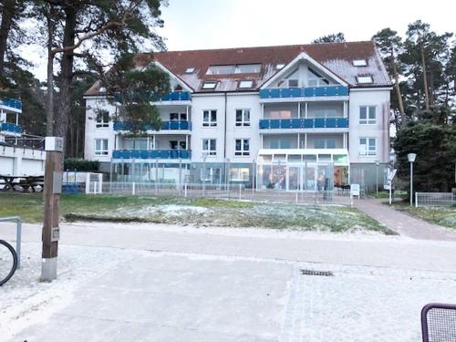 un gran edificio blanco con ventanas azules en una calle en Blaumuschel Haus A Wohnung 24 - DH en Lubmin