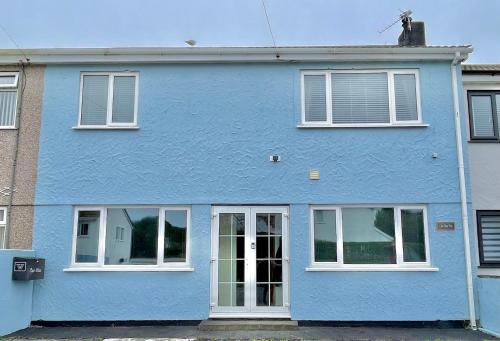a blue house with white windows on a street at Cae Glas Apartments in Holyhead