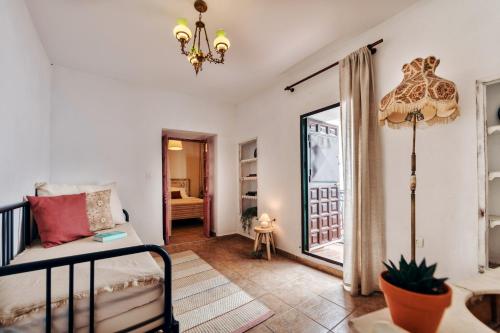 a living room with a bed and a mirror at Encanto Guesthouse in Canillas de Aceituno