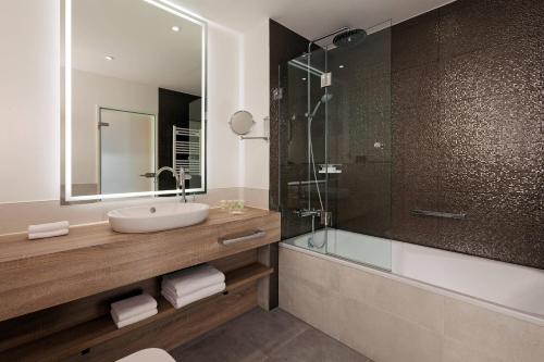 a bathroom with a sink and a glass shower at Courtyard by Marriott Hamburg Airport in Hamburg