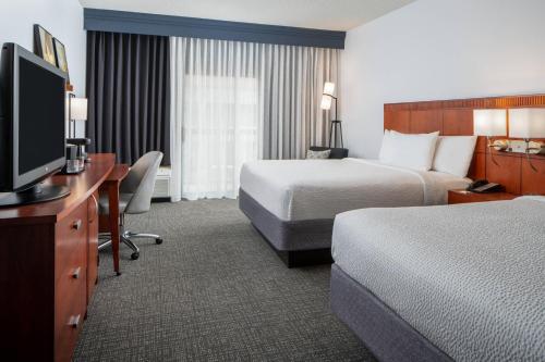 a hotel room with two beds and a flat screen tv at Courtyard by Marriott Dulles Airport Herndon/Reston in Herndon