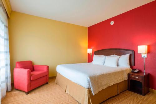 sypialnia z łóżkiem i czerwoną ścianą w obiekcie Courtyard Wilmington Brandywine w mieście Wilmington